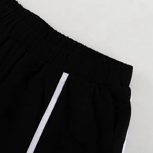 Detail van de elastische tailleband met witte contraststrepen op een zwarte gebreide broek