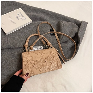 Detail of beige leather bag with embossed lotus and carp pattern on fabric background