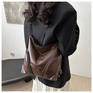 Detail view of large dark brown soft leather shoulder bag with diagonal zipper design