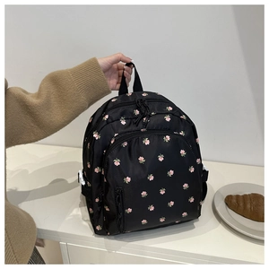 Detail eines Mini-Rucksacks aus Nylon mit rosa Blumenmuster auf weißem Schreibtisch