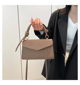Detail of woven texture and decorative knotted handle with gold rings on crossbody bag