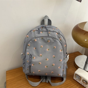 Detail eines grauen Mini-Rucksacks mit rosa Tulpenmuster und vorderer Reißverschlusstasche