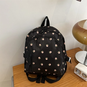 Nahaufnahme eines schwarzen Nylon-Minirucksacks mit Blumenmuster auf Holztisch