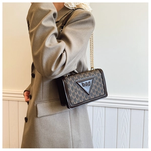 Piccola borsa quadrata marrone con monogramma e catena indossata da una modella