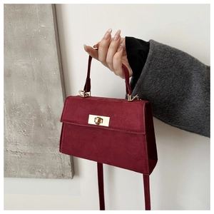Détail d'un sac à bandoulière en cuir bordeaux avec fermoir rotatif doré poli