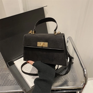 Détail du sac bandoulière en daim noir avec fermoir carré doré et poignée élégante