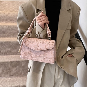 Pink embossed handbag with lotus and koi patterns shown in a stylish lifestyle setting