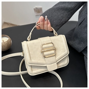 Détail du sac bandoulière crème en cuir mat avec une boucle dorée élégante et raffinée