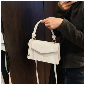 Nahaufnahme der weißen geprägten Blumentasche mit geflochtenem Griff und Golddetails