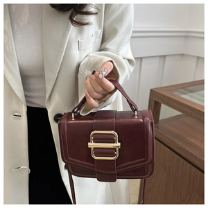 Gros plan d'un sac à main bordeaux en cuir avec boucle dorée et poignée supérieure
