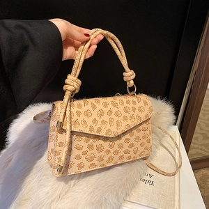 Beige Umhängetasche mit Kleeblatt-Print und geknotetem Griff auf weißem Kunstpelz