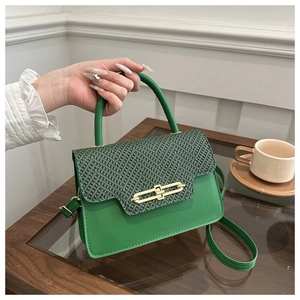 Detail of green structured box bag with textured flap and gold metal turn-lock closure