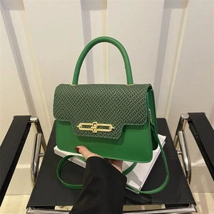 Detail of green hard-shell box bag showing woven black texture and golden metal lock