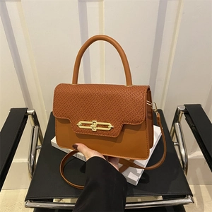 Close-up of caramel brown box bag with faux crocodile texture and gold metal turn lock