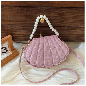 Detail of a pink shell bag with glitter finish, pearl handle and fine chain strap