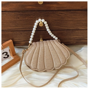 Detailed macro view of shell-shaped handbag featuring premium pearls handle and glitter fabric