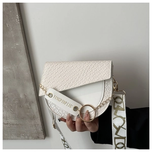 Détail du sac selle crème avec texture tissée, détails dorés et large bandoulière