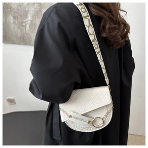 Détail du sac selle blanc à motif crocodile avec bandoulière siglée et chaîne en métal