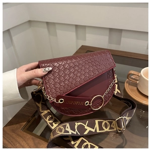 Détail du sac selle bordeaux avec texture gaufrée et bandoulière en toile à motifs