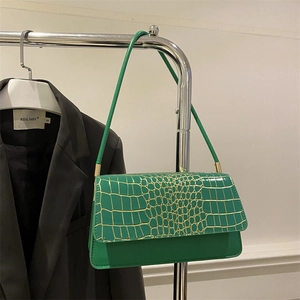 Detail of green crocodile texture flap on minimalist rectangular shoulder bag