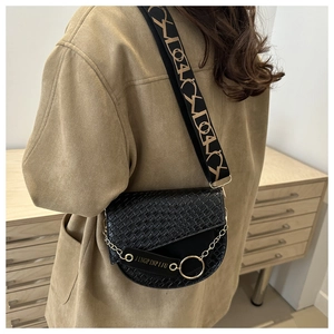 Détail du sac de selle noir à texture crocodile et bandoulière géométrique