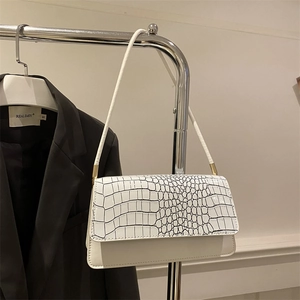 Detail of white crocodile embossed texture on a minimalist retro shoulder bag