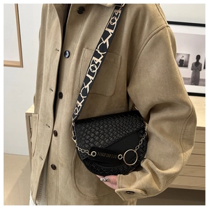 Détail du sac selle noir tressé avec anneau doré et bandoulière en jacquard