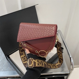 Détail du sac à main bordeaux en cuir avec texture crocodile et bandoulière tissée