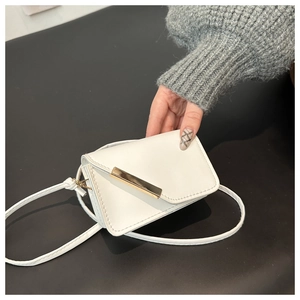 Dettaglio mini borsa a tracolla bianca con chiusura a barra dorata e tracolla sottile