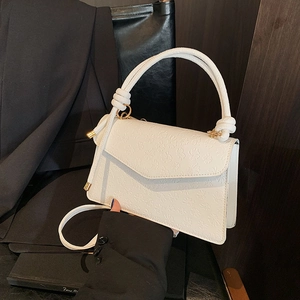 Weiße quadratische Tasche mit Prägung, Knotengriff und Schultergurt in kontrastreicher Ansicht