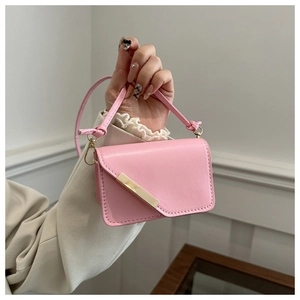 Dettaglio borsa a tracolla in pelle rosa con elegante barra in metallo dorato e patta