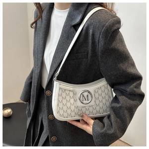 Detailed view of the white baguette bag with M-monogram pattern and silver metal buckle