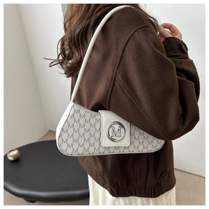 Detail of white semi-circle shoulder bag featuring repeating M-pattern and silver metal logo