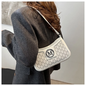 Detail of a chic cream shoulder bag with M-pattern and round silver metal buckle