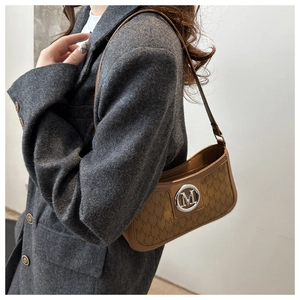 Brown moon bag with M-letter monogram and silver buckle styled with a tweed coat