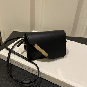 Dettaglio della piccola borsa a tracolla nera con una barra asimmetrica in metallo oro