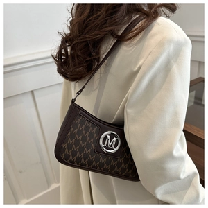 Macro view of dark brown monogram pattern and silver M logo on retro shoulder bag