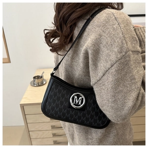Detail of black underarm bag featuring M-pattern monogram and silver metal logo