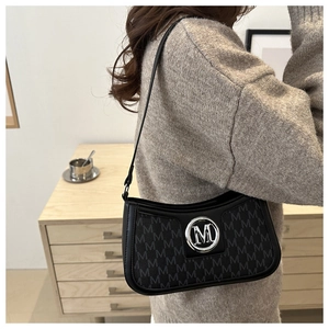 Close-up of black retro shoulder bag with M letter pattern and silver metal hardware