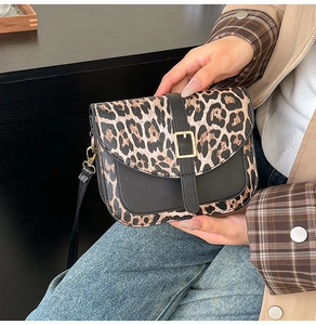 Detailed close-up of leopard print panel and gold buckle on a stylish crossbody saddle bag