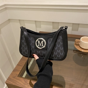 Detail of a retro black and grey monogram shoulder bag with a silver metal M logo