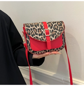 Detail of red and leopard print patchwork shoulder bag with golden buckle and slim strap