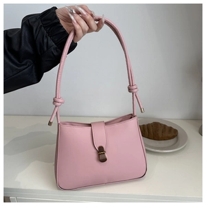 Detail of pink PU leather underarm bag featuring decorative knot strap and metal clasp