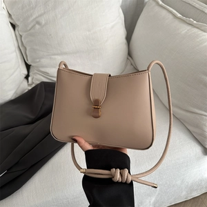 Detailed view of milk tea PU leather bag with gold buckle and knotted strap accents