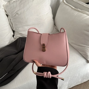 Close-up of pink PU leather handbag with bronze metal snap and knotted shoulder strap