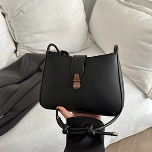 Detail of matte black PU leather bag with retro bronze buckle and knotted strap