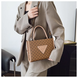 Detail showing brown patterned tote bag with leather triangle patch and crossbody strap