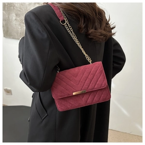 Close-up of a burgundy quilted velvet crossbody bag with elegant gold chain strap