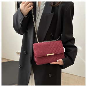 Macro detail of wine red quilted chain bag with gold metal trim and chevron pattern