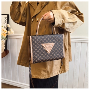 Close-up of brown geometric tote bag with leather logo patch and top handles